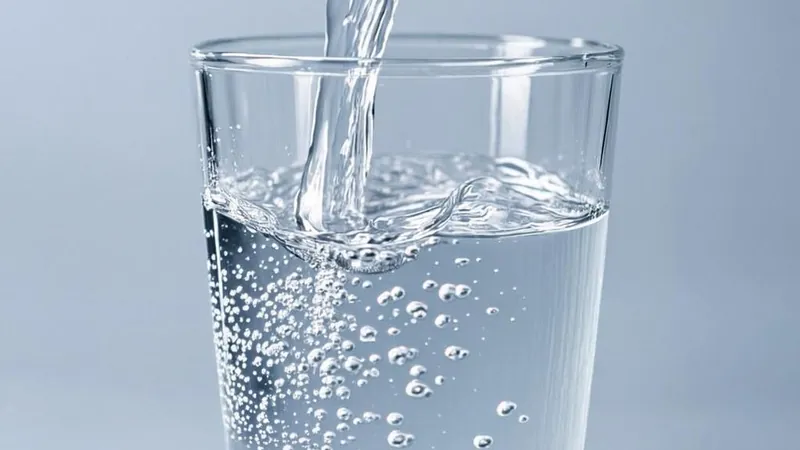 An empty glass filling with clear water under soft light